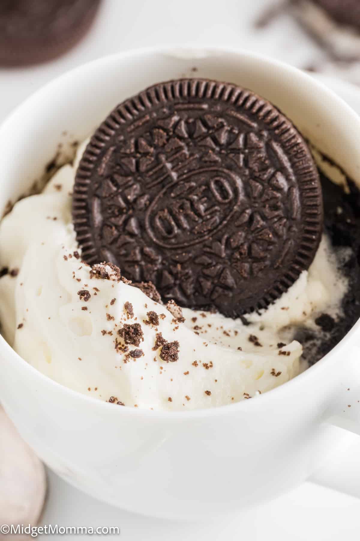 Close up photo of Microwave Oreo Mug Cake Recipe topped with whipped cream and an Oreo Cookie