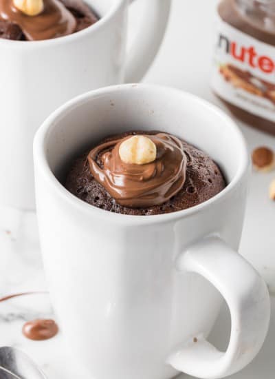 close up photo of Nutella microwave Mug Cake topped with nutella hazelnut spread and a hazelnut