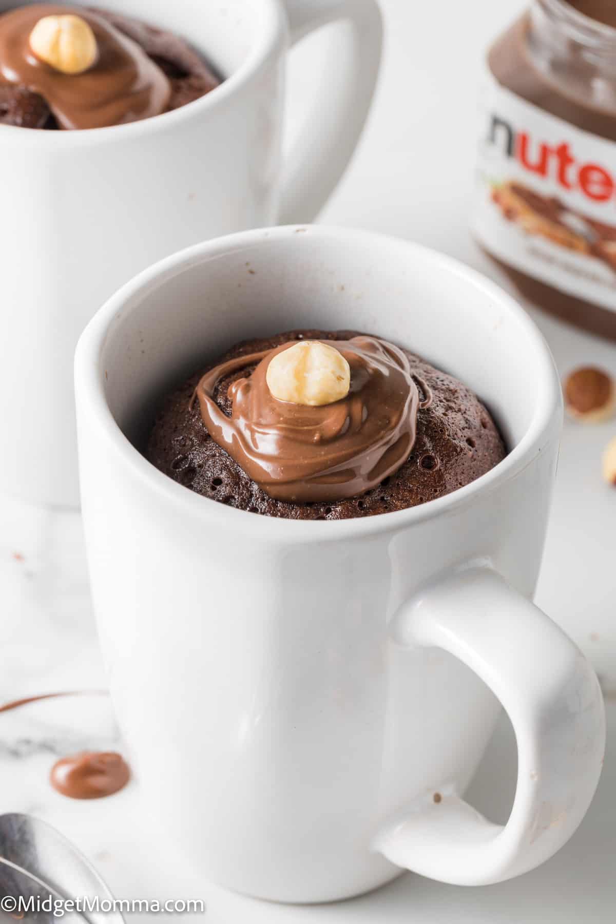 close up photo of Nutella microwave Mug Cake in a white mug topped with nutella hazelnut spread and a hazelnut