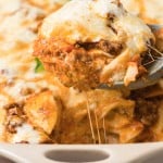 large serving spoon scoping Easy Baked Ravioli Casserole out of the baking dish.