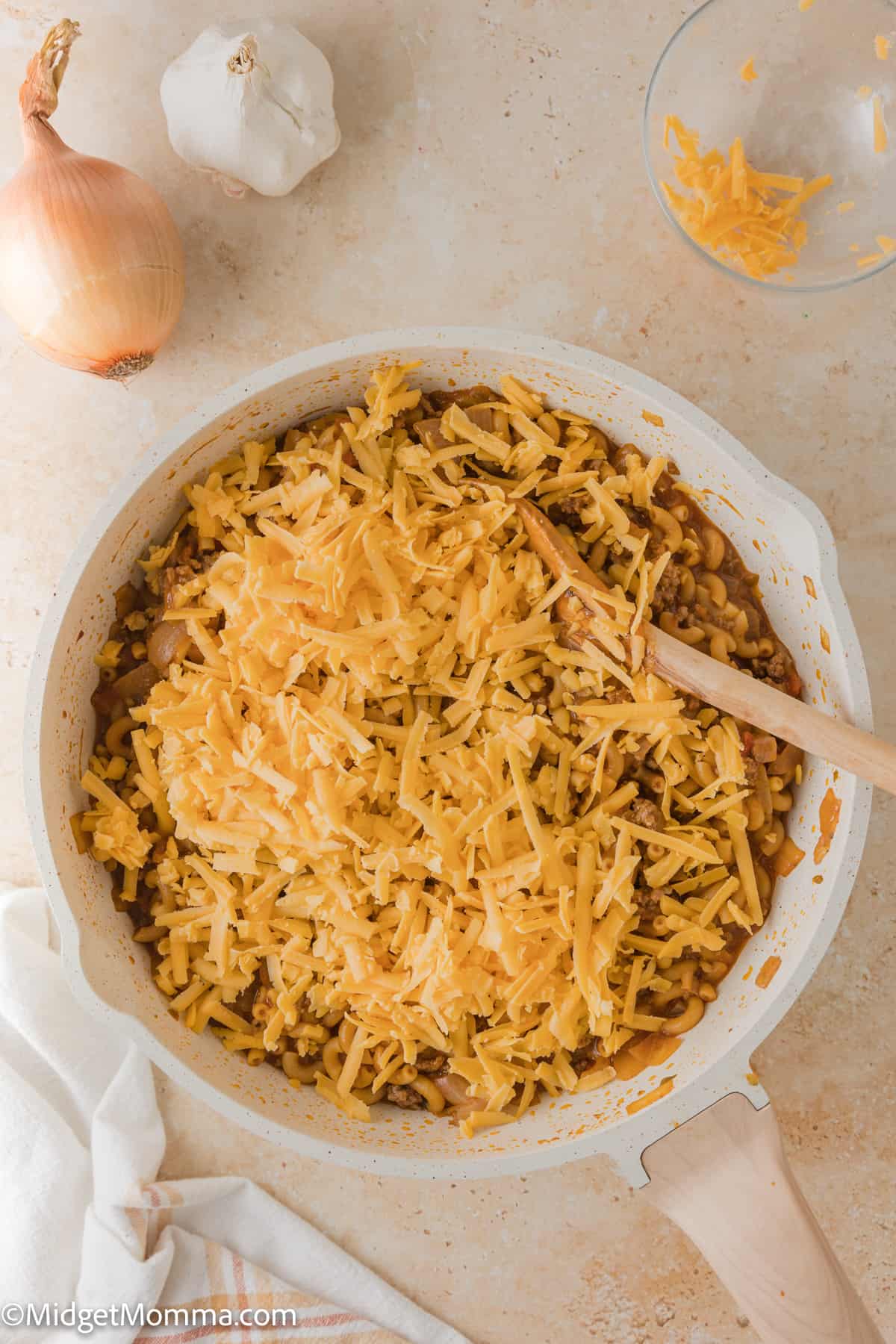shredded cheese being added to cheeseburger pasta hamburger helper recipe in the skillet