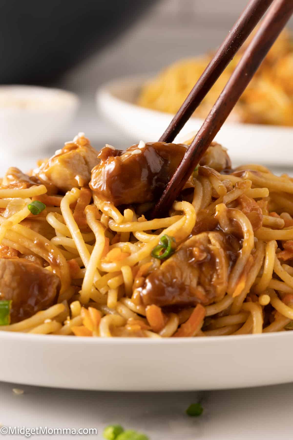 close up photo of a plate of Thai Peanut Noodles with Chicken being eaten with chop sticks