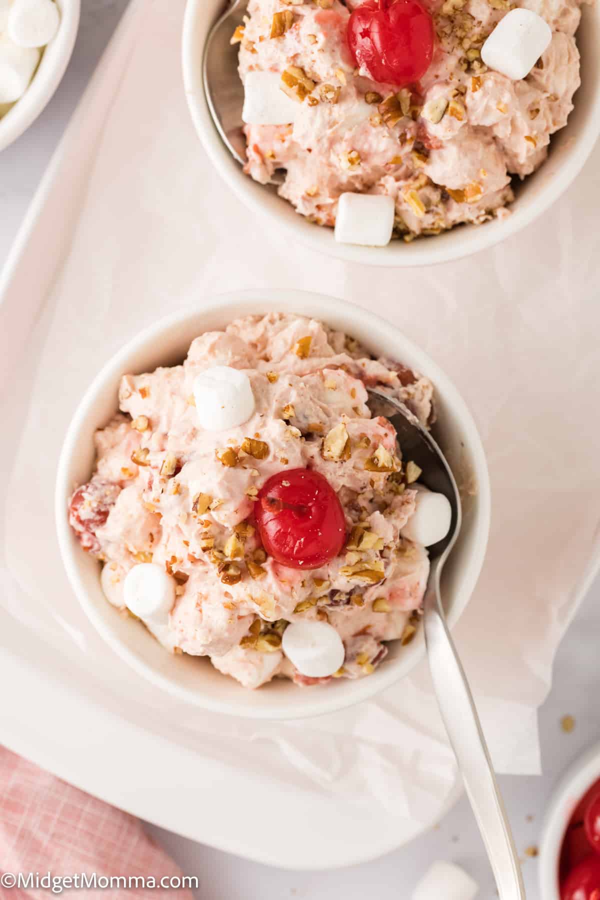 overhead photo of a white bowl with Cherry fluff topped with mini marshmallows and a cherry