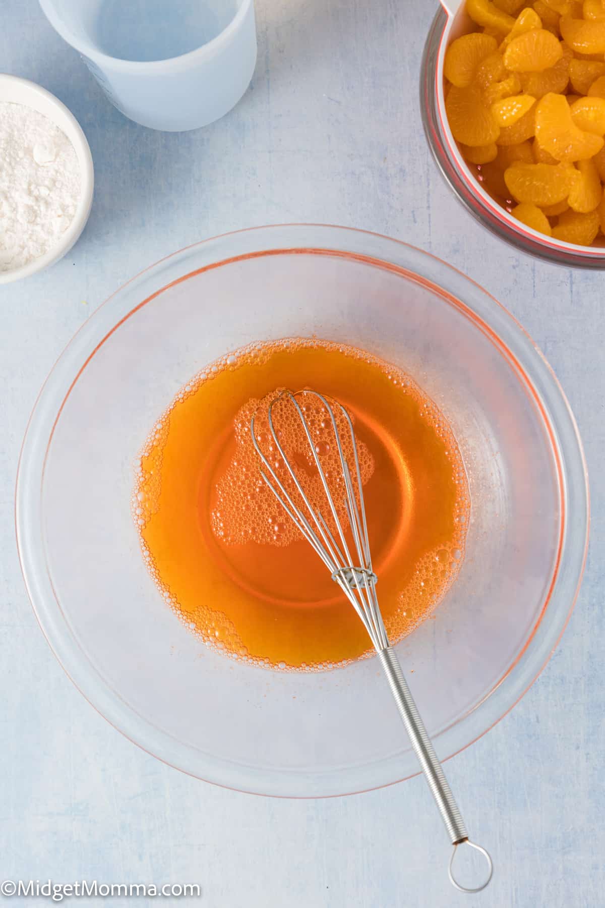 orange jello powder and water in a mixing bowl