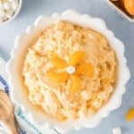 overhead photo of a white bowl filled with fluffy orange fluff salad topped with mandarin orange slices