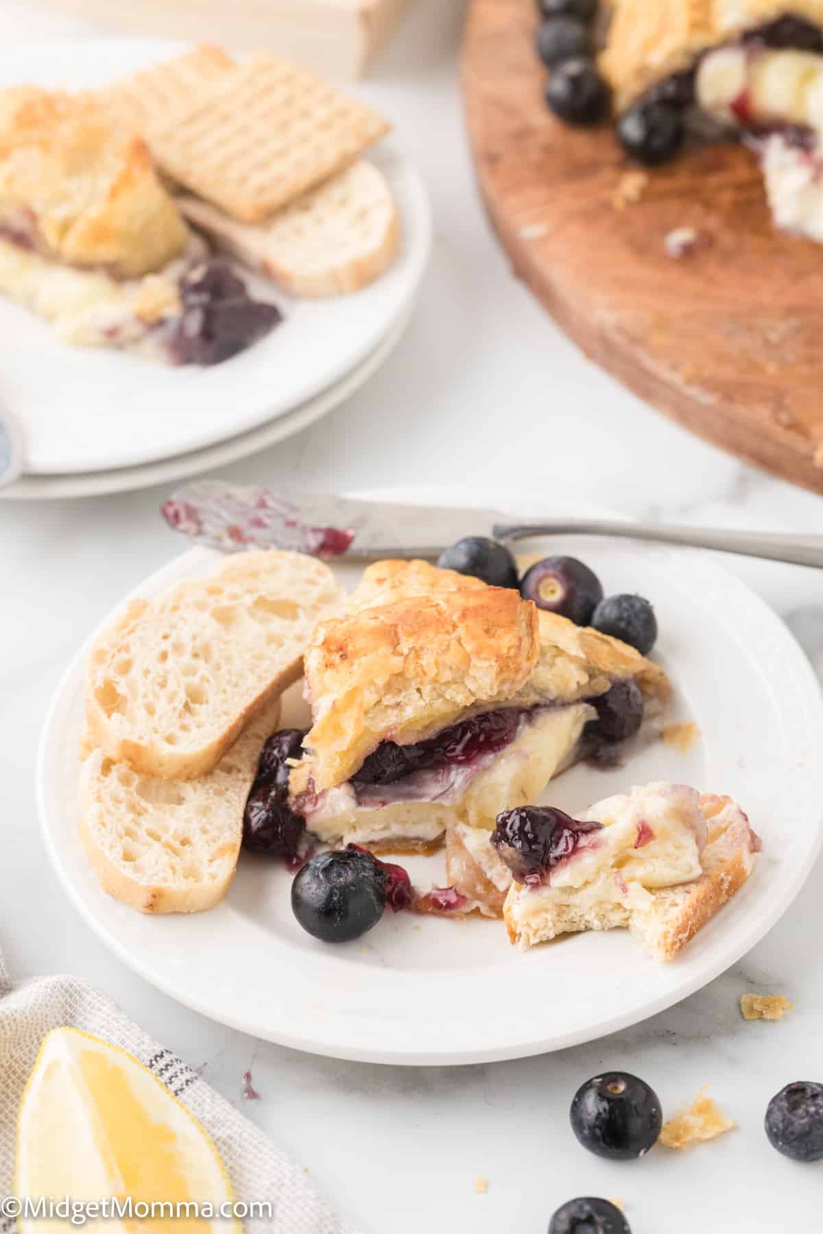 Baked Brie in Puff Pastry with Blueberry Pie Filling served on a plater with crusty bread