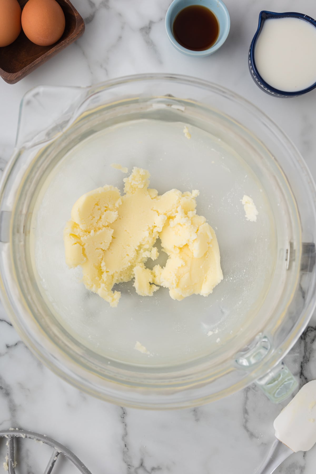 Butter in a glass bowl next to eggs and other ingredients.