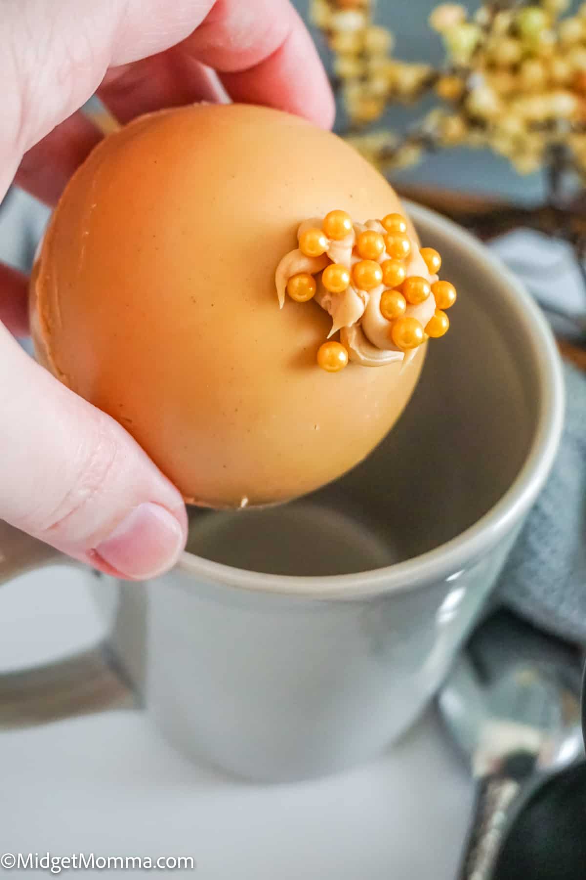 peanut butter hot chocolate bomb being placed in to a mug