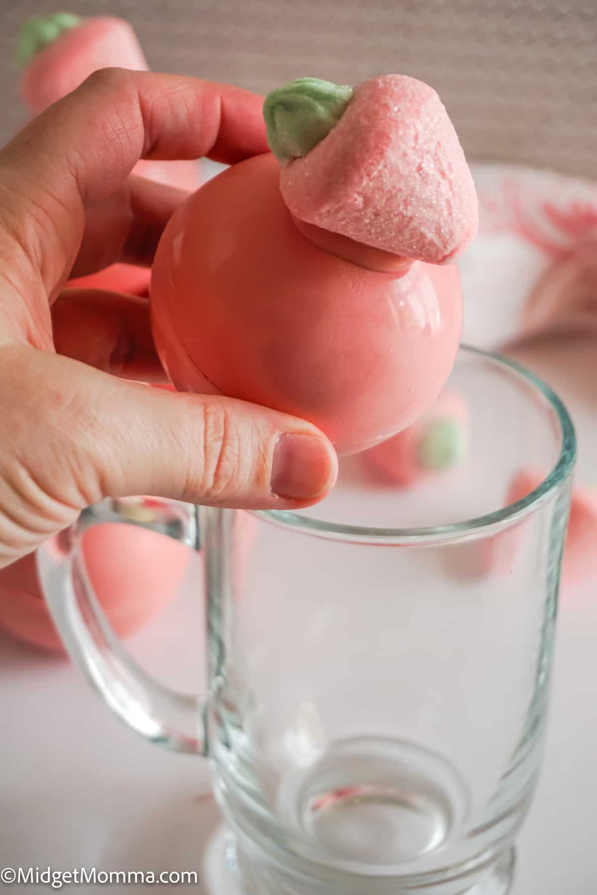 strawberry hot chocolate bombs being put into a mug