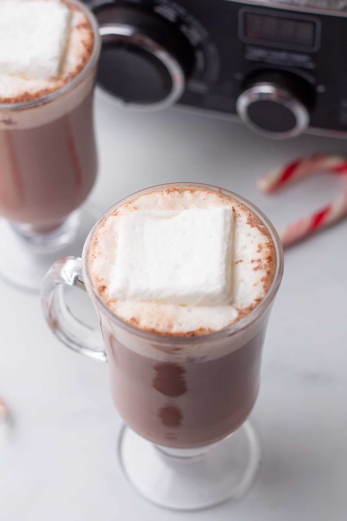 Two glasses of hot chocolate with marshmallows and candy canes.