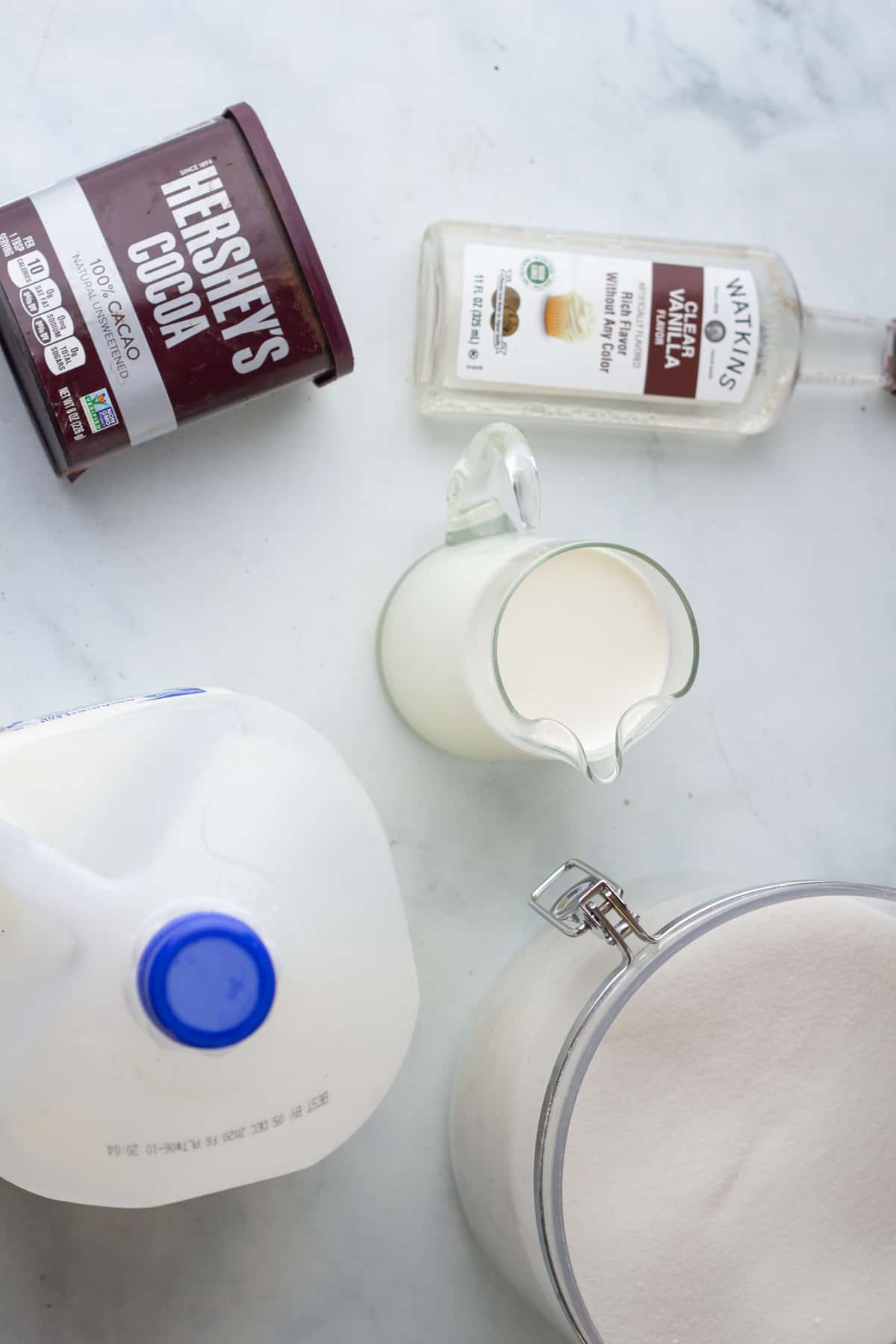 The ingredients for a milkshake are laid out on a marble table.