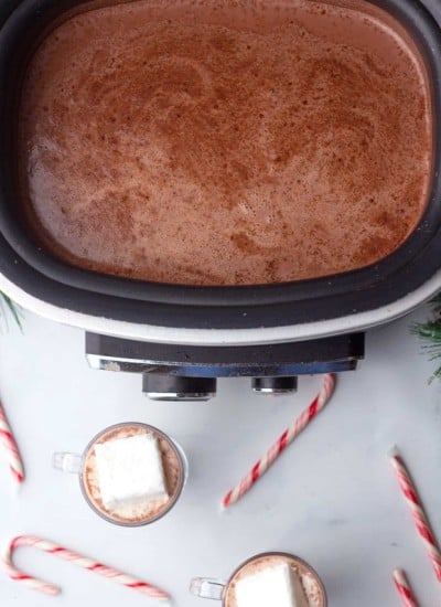 A crock pot filled with hot chocolate and candy canes.
