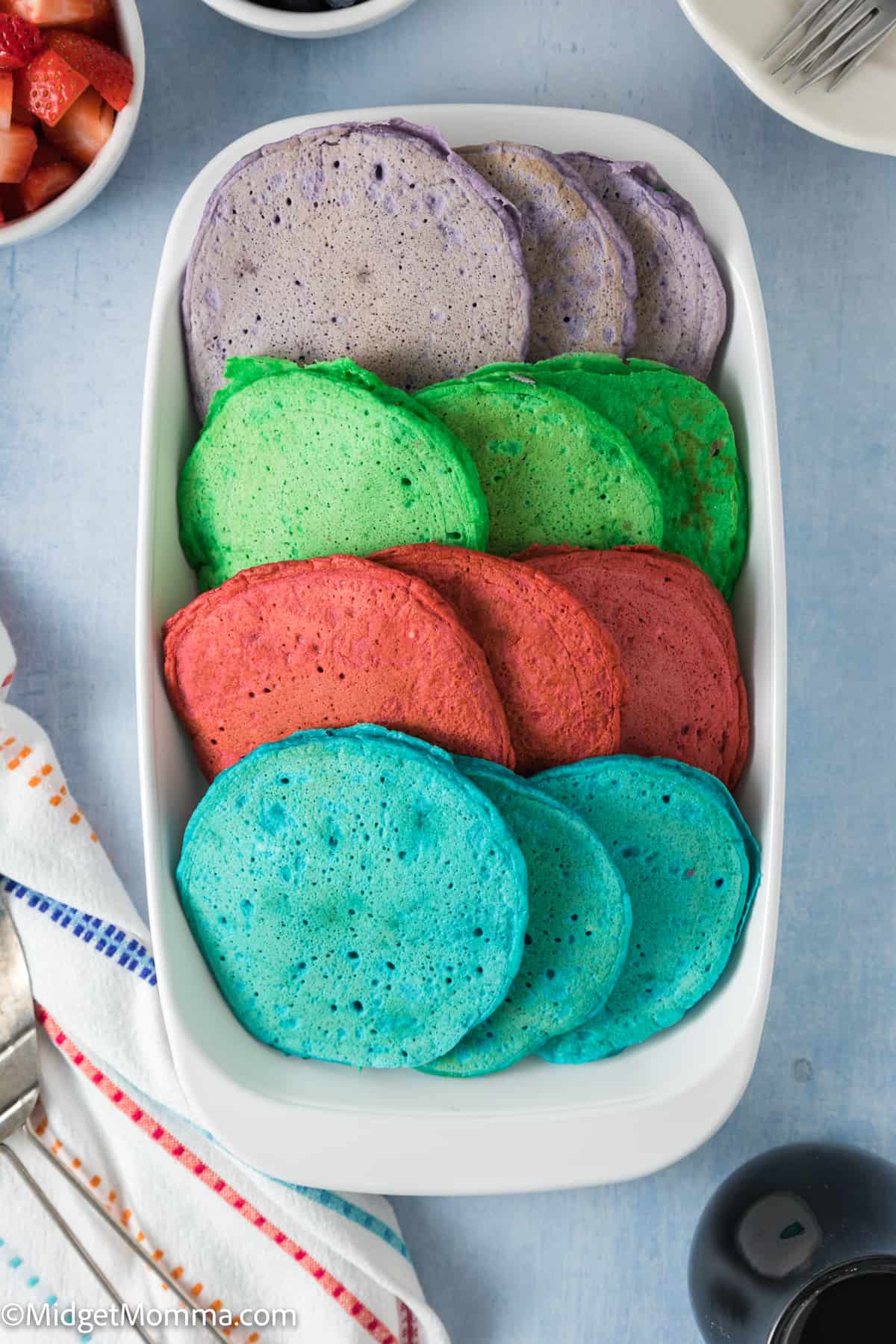 Rainbow pancakes in a white serving dish.