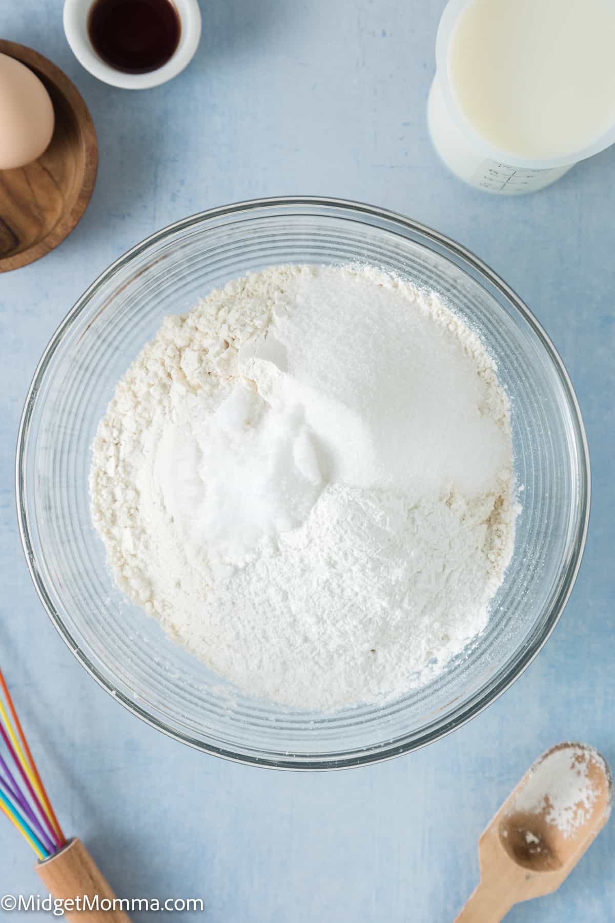 A bowl of flour, and other ingredients on a blue background.