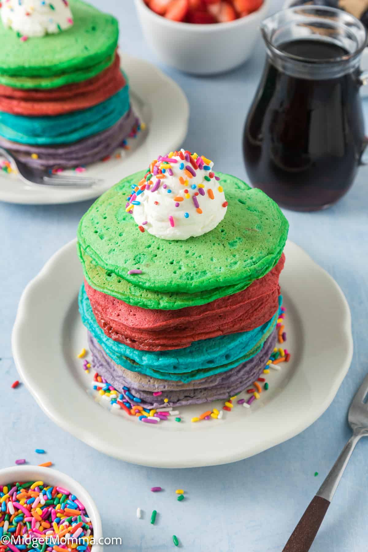 Rainbow pancakes with whipped cream and sprinkles.