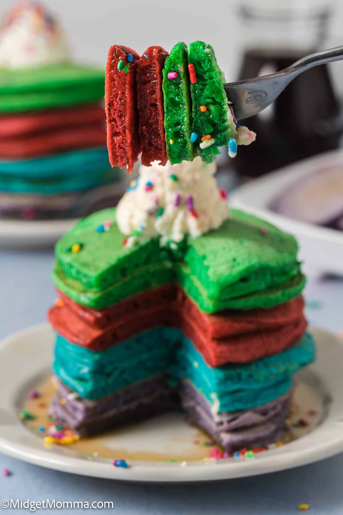 A stack of colorful pancakes on a plate with a fork.