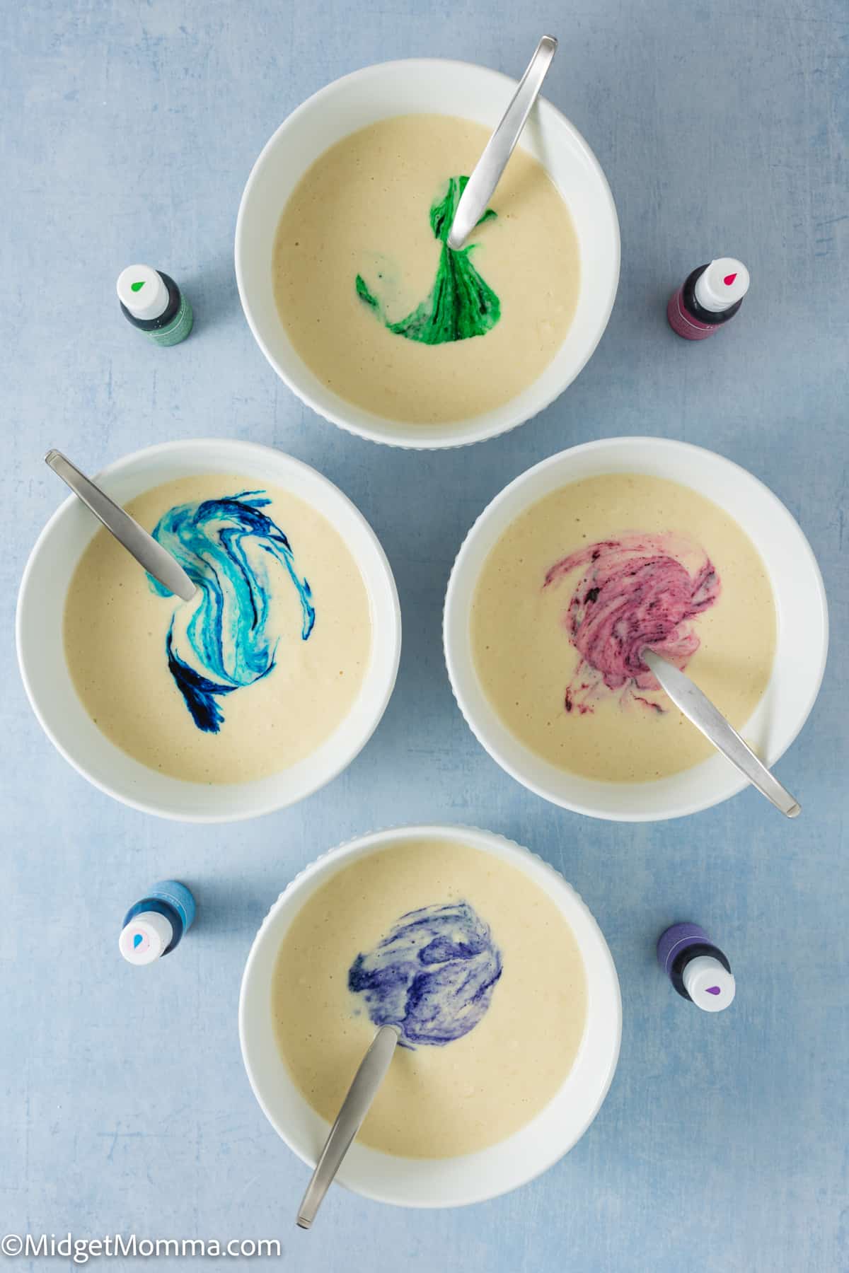 Four bowls with different colors of food coloring added to the batter in them.