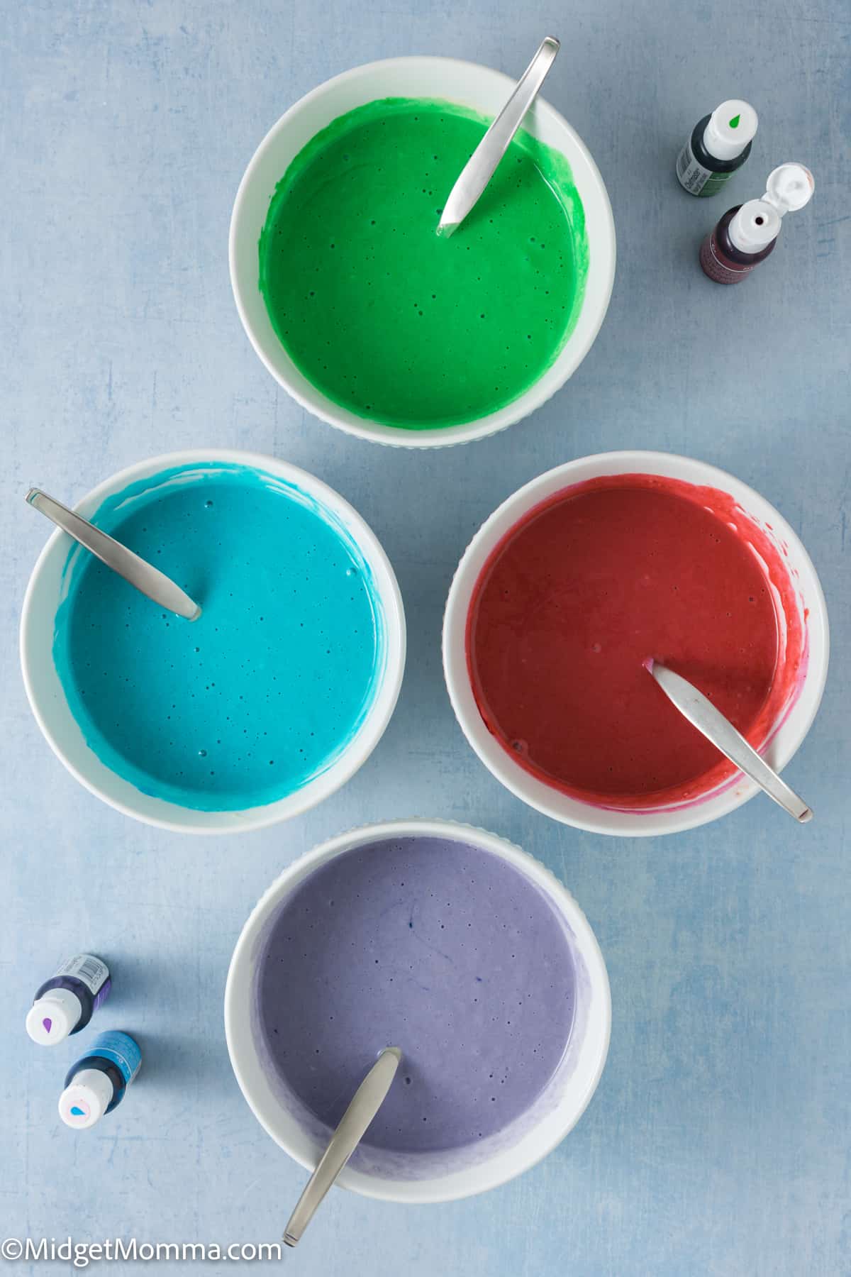 Four bowls with different colors of pancake batter in them.