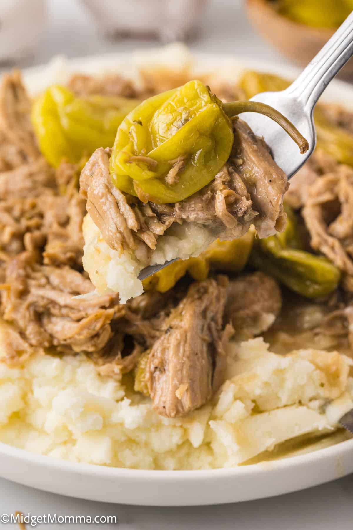 A fork with a bite of shredded mississippi pork roast on it. 