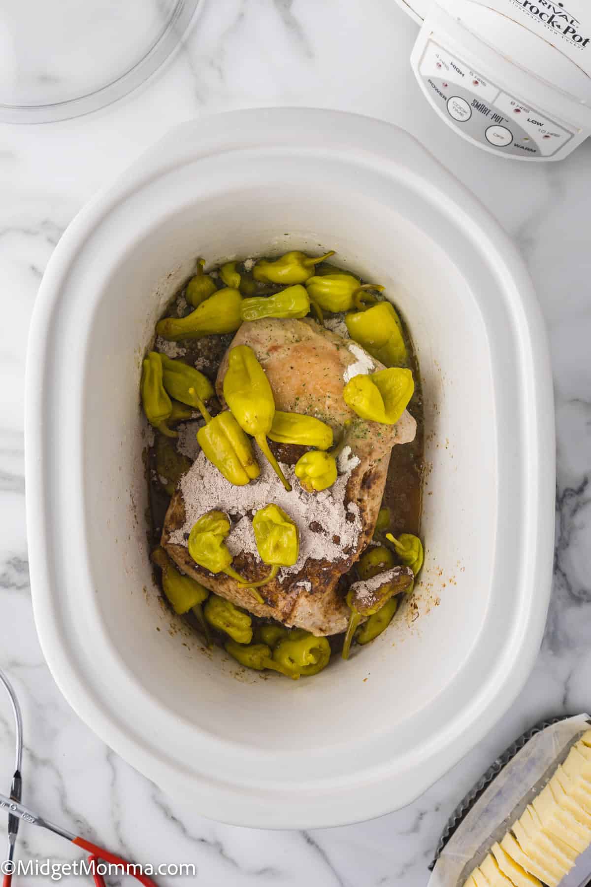 pork roast in a slow cooker topped with dry ranch mix, au jus mix and peppers.