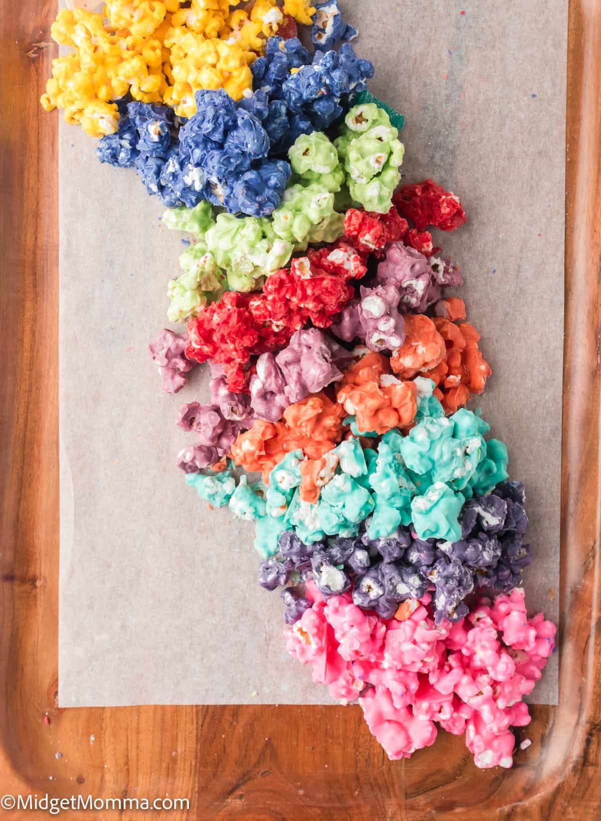 Colorful popcorn arranged in a gradient pattern on a wooden surface.