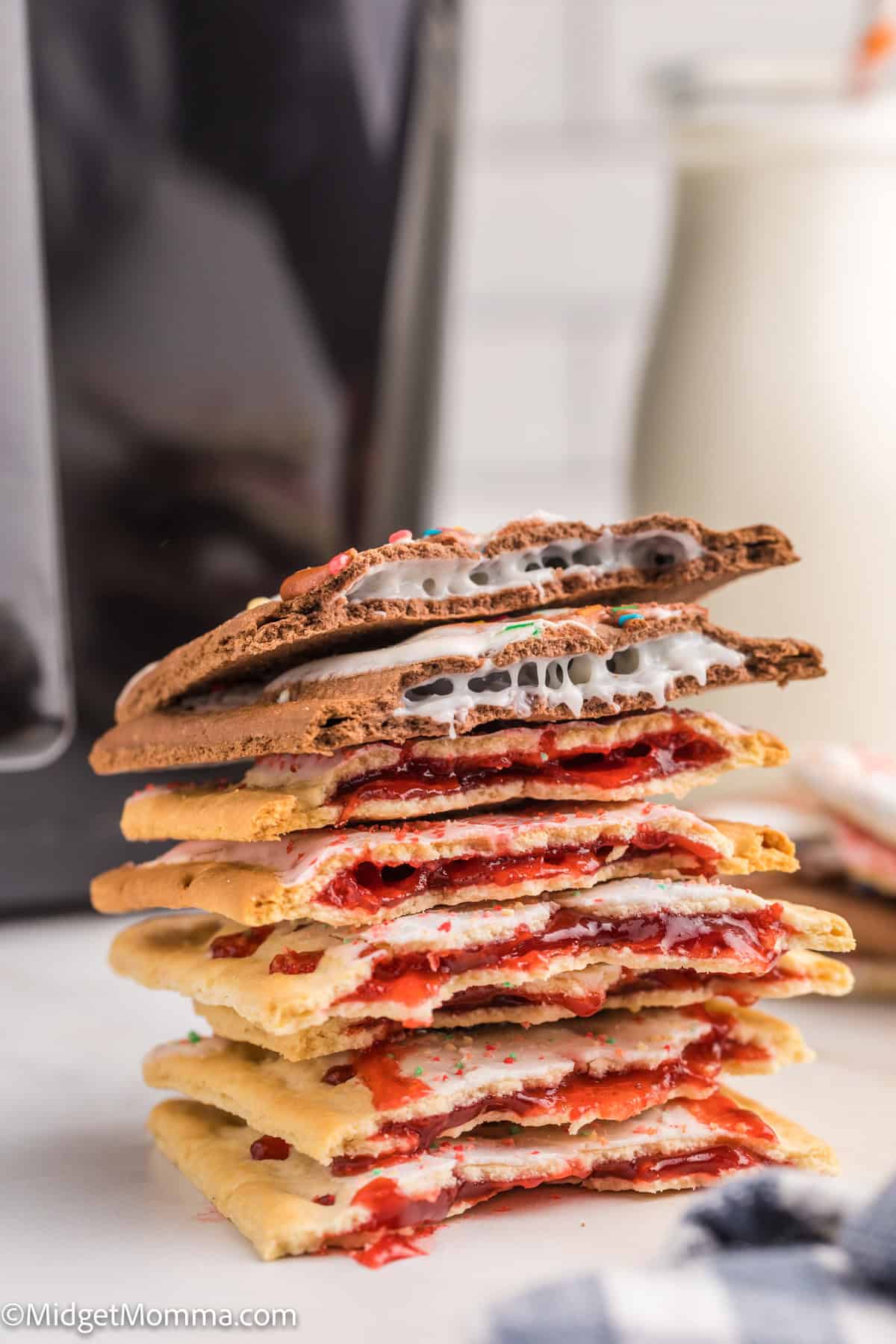 A stack of toasted Pop-Tarts, some with chocolate and others with fruit filling, are shown with visible fillings and a glass of milk in the background.